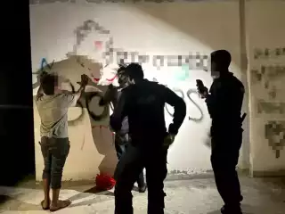 Police search two individuals in an area suspected to be frequented by criminals