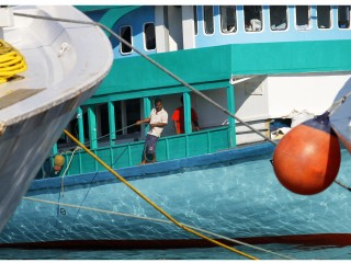A boatsman helps pulls a local Dhoani to a harbour