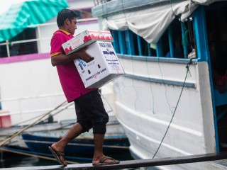 A ferry crewman loads a case of eggs for transport to the outlying islands