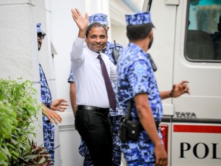 MP Saud waves to journalists as police escort him after a court hearing