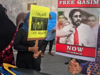 An opposition support holds up a 'Free Qasim Now' poster a protest calling for Qasim Ibrahim's release