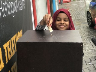 A child makes a donation to the Rohingya fund