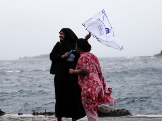 A woman photographed struggling against wind during showers in capital city Malé