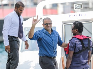 Jailed Vice President Ahmed Adeeb gestures to journalists as officers escort him to detention
