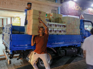 A hired hand helps unload a truck of cargo