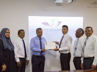 Addu City Mayor Abdulla Sodiq confers a letter of recognition to councilor Faisal (L)