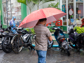 A pedestrian crossing a road in capital city Malé. Moderate rain and even continuous drizzle  can cause flooding in the street\'s Maldives\' capital city
