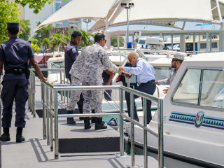 Former President Maumoon Abdul Gayoom escorted out of a speed boat at a docking harbour in capital city Malé
