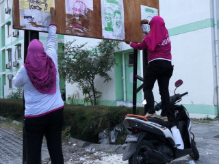 ރައީސް ޔާމީން 2018 ޖަހާފައިވާ ޓީޝާޓްތަކެއް ލައިގެން ތިބި ބަޔަކު ކޯލިޝަންގެ ޕޯސްޓަރުތައް ނައްޓުވަނީ