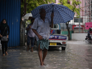 A man walks through a flooded road in capital city Malé
