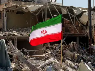 މާރިޗު 3، 2026 ގައި ތެހެރާންގެ ފިރުދޯސީ މައިދާނުގެ ކައިރިން ސުންނާފަތިވެފައިވާ މީހުން ދިރިއުޅޭ އިމާރާތެއްގެ ކައިރީގައި ހުރި ކުނިތަކާއި ގައުކުނޑިތަކުގެ ތެރޭގައި އީރާނުގެ ދިދައެއް ހަރުކޮށްފައި.