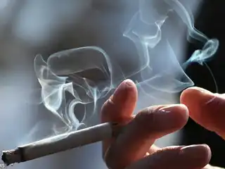 A person holding a lit cigarette.