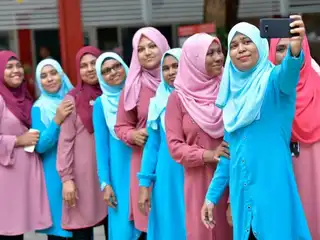 ސްކޫލެއްގެ ބައެއް ޓީޗަރުން ފޮޓޯއެއް ނަގަން ހުއްޓިލައިގެން ތިބި މަންޒަރު.