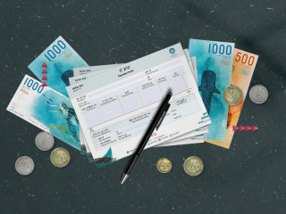 A scatter of MVR one and MVR two coins with notes of MVR 1,000 and MVR 500 positioned beneath MIRA's tax payment forms