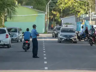A police officer manages traffic on a street in Fuvahmulah City.