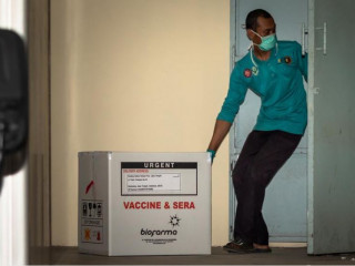 އިންޑޮނޭޝިޔާގެ ޖާވާގައި ސިނޯފަރމް ވެކްސިންގެ ފޮށިގަނޑެއް މީހަކު ގުދަނަށް ވައްދަނީ