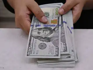 މަނީ އެކްސްޗޭންޖެއްގައި މަސައްކަތްކުރާ ކްލާކަކު އެމެރިކާ ޑޮލަރުގެ ނޫޓުތަތަކެއް ގުނަނީ.