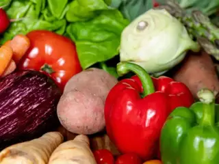 A collection of vegetables lies on a table in the kitchen. 