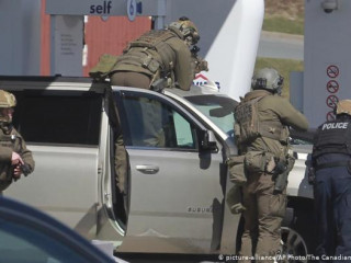Royal Canadian Mounted Police officers surround a suspect at a gas station in Enfield, Nova Scotia