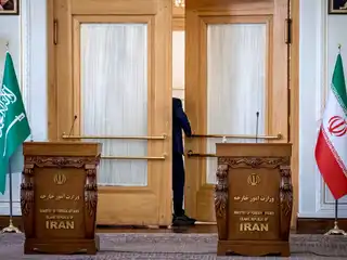 ތެހެރާންގައި ހުންނަ އީރާނުގެ ފޮރިން މިނިސްޓްރީގެ އިމާރާތުގައި 2023 ޖޫން 17 ވަނަ ދުވަހު ބޭއްވި ބައްދަލުވުމެއްގެ ތެރެއިން، އީރާނުގެ ދިދަ އާއި ސައުދީ އަރަބިއްޔާގެ ގައުމީ ދިދަ ކައިރީގައި ކޮންފަރެންސް ހޯލެއްގެ ދޮރުމަތީގައި ސައުދީގެ އޮފިޝަލަކު މަޑުކޮށްލައިގެން.