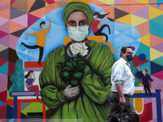 ބްރެޒިލްގައި މާސްކު އަޅައިގެން ހުރި ކުރެހުމެއް ކުރަހާފައި ހުރި ފާރެއް ކައިރިން މީހަކު ހިނގާފައިދަނީ