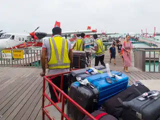 މާލޭ އިންޓަނޭޝަނަލް އެއާޕޯޓުގެ ސީޑްރޯމްގައި ޓްރާންސް މޯލްޑިވިއަން އެއާވޭސްގެ ސީޕްލޭންތަކަށް ފަތުރުވެރިންގެ ލަގެޖު ޕޯޓަރުން ގެންދަނީ