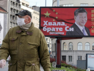 ޗައިނާގެ ރައީސް ފެންނަ ބިލްބޯޑެއް ކުރިމަތިން މާސްކު އަޅައިގެން މީހަކު ހިނގާފައިދަނީ