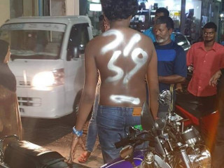 The photo shows the man shirtless with ‘thief’ sprayed on his back as people look on