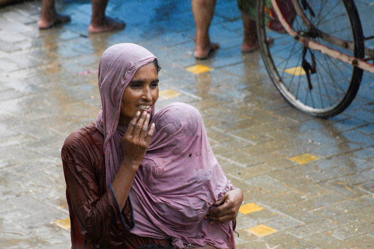 ޕާކިސްތާނުގެ ހައިދަރްއާބާދުގައި ހުޅަނގު މޫސުމުގެ ވާރެއިން ފެންބޮޑުވެފައިވާ މަގެއްގައި ހިނގާފައިދިޔަ އަންހެނަކު އޭނާގެ ތުއްތު ދަރިފުޅު ވާރެއިން ހިމާޔަތް ކުރަނީ - ފޮޓޯ: ރޮއިޓަރސް