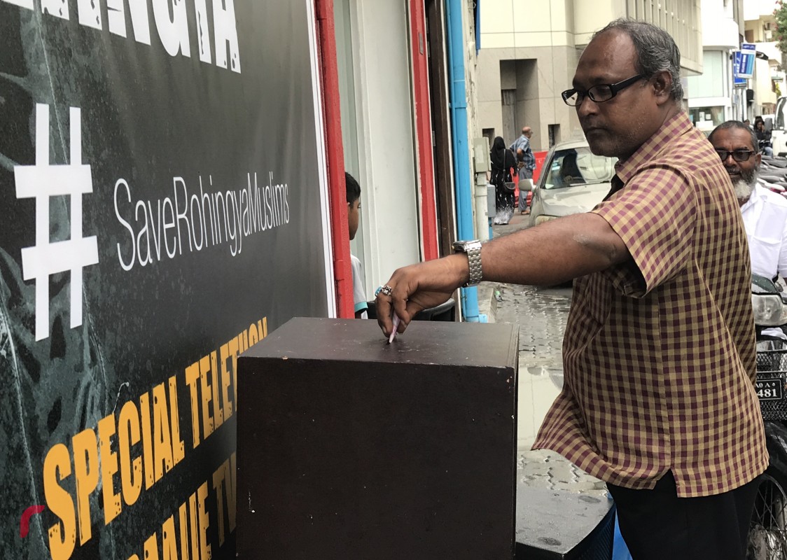 ސެޕްޓެމްބަރު 11، 2017: ދިވެހިރައްޔިތުން ރޮހިންޖާ މުސްލިމުންނާއެކު ޓެލެތޯނަށް އެހީވުމަށް ރާއްޖެ ޓީވީ ކުރިމަތީގައި ބަހައްޓާފައިވާ ފަންޑު ފޮއްޓަށް މީހަކު ފައިސާ ހަދިޔާކުރަނީ