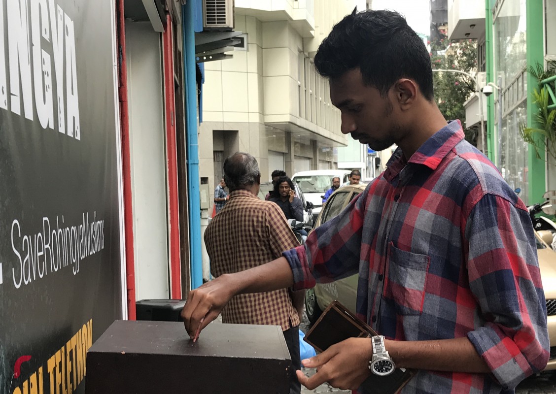 ސެޕްޓެމްބަރު 11، 2017: ދިވެހިރައްޔިތުން ރޮހިންޖާ މުސްލިމުންނާއެކު ޓެލެތޯނަށް އެހީވުމަށް ރާއްޖެ ޓީވީ ކުރިމަތީގައި ބަހައްޓާފައިވާ ފަންޑު ފޮއްޓަށް މީހަކު ފައިސާ ހަދިޔާކުރަނީ