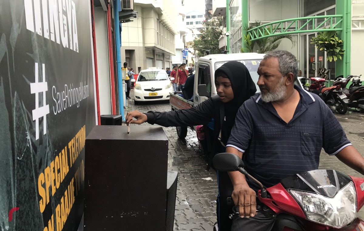 ސެޕްޓެމްބަރު 11، 2017: ދިވެހިރައްޔިތުން ރޮހިންޖާ މުސްލިމުންނާއެކު ޓެލެތޯނަށް އެހީވުމަށް ރާއްޖެ ޓީވީ ކުރިމަތީގައި ބަހައްޓާފައިވާ ފަންޑު ފޮއްޓަށް މީހަކު ފައިސާ ހަދިޔާކުރަނީ