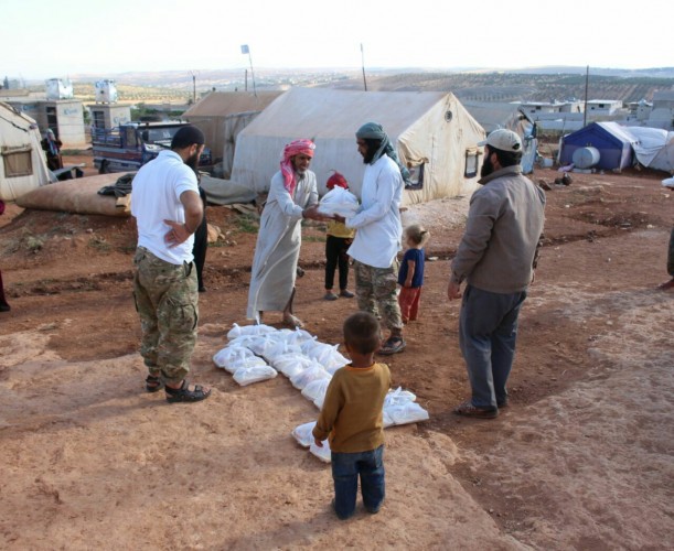 Combatants distribute parcels containing stable food items at a camp 