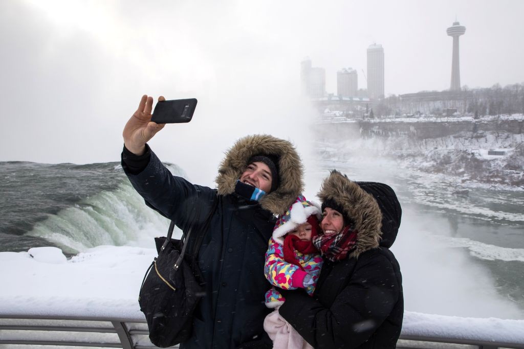 ޖެނުއަރީ 2، 2018 : އެމެރިކާގެ އޮންޓާރިއޯގައި ހުންނަ ނައެގްރާ ފޯލްސްގެ ފެންގަނޑު ގަނޑވެފައިވާ މަންޒަރު ބަލަންގޮސްތިބި ފަތުރުވެރިންތަކެއް ސެލްފީއެއް ނަގަނީ