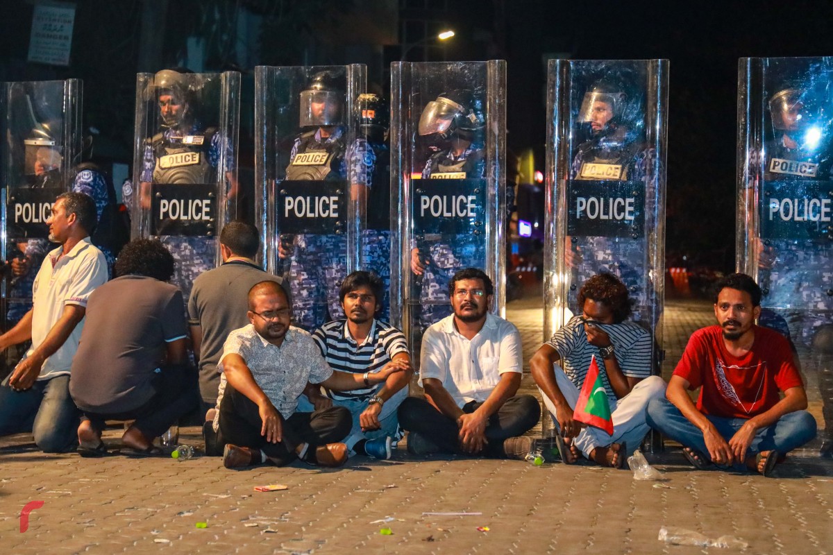 ފެބްރުއަރީ 1، 2018: ފުލުހުންގެ ޝީލްޑްތަކުގެ ކުރިމަތީގައި މީހުން އިށީނދެ ލައިގެނެ -- ފޮޓޯ: މުހައްމަދު ޝަރުހާން