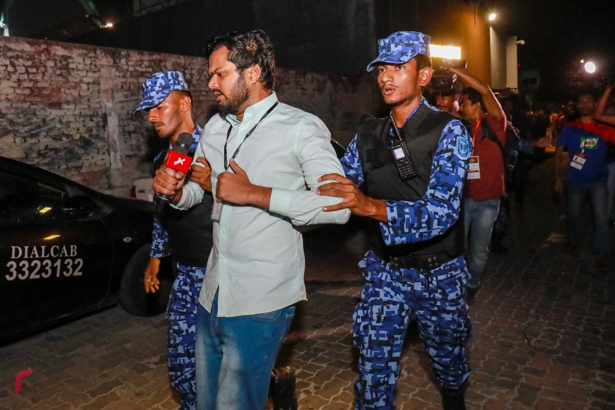 ފެބްރުއަރީ 2، 2018: މުޒާހަރާ ކަވަރުކުރަމުން ދިޔަ ރާއްޖެޓީވީގެ ނޫސްވެރިޔާ ހަސަން ހުސައިން ގަދަކަމުން ސަރަހައްދުން ދުރުކުރަނީ -- ފޮޓޯ: މުހައްމަދު ޝަރުހާން