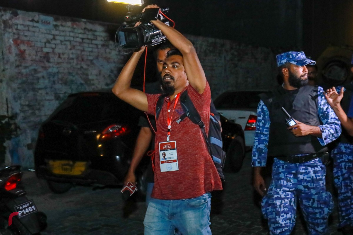 ފެބްރުއަރީ 2، 2018: މުޒާހަރާ ކަވަރުކުރަމުން ދިޔަ ރާއްޖެޓީވީގެ ކެމެރާމަން އާދަމް ޒަރީރު ގަދަކަމުން ސަރަހައްދުން ދުރުކުރަނީ -- ފޮޓޯ: މުހައްމަދު ޝަރުހާން