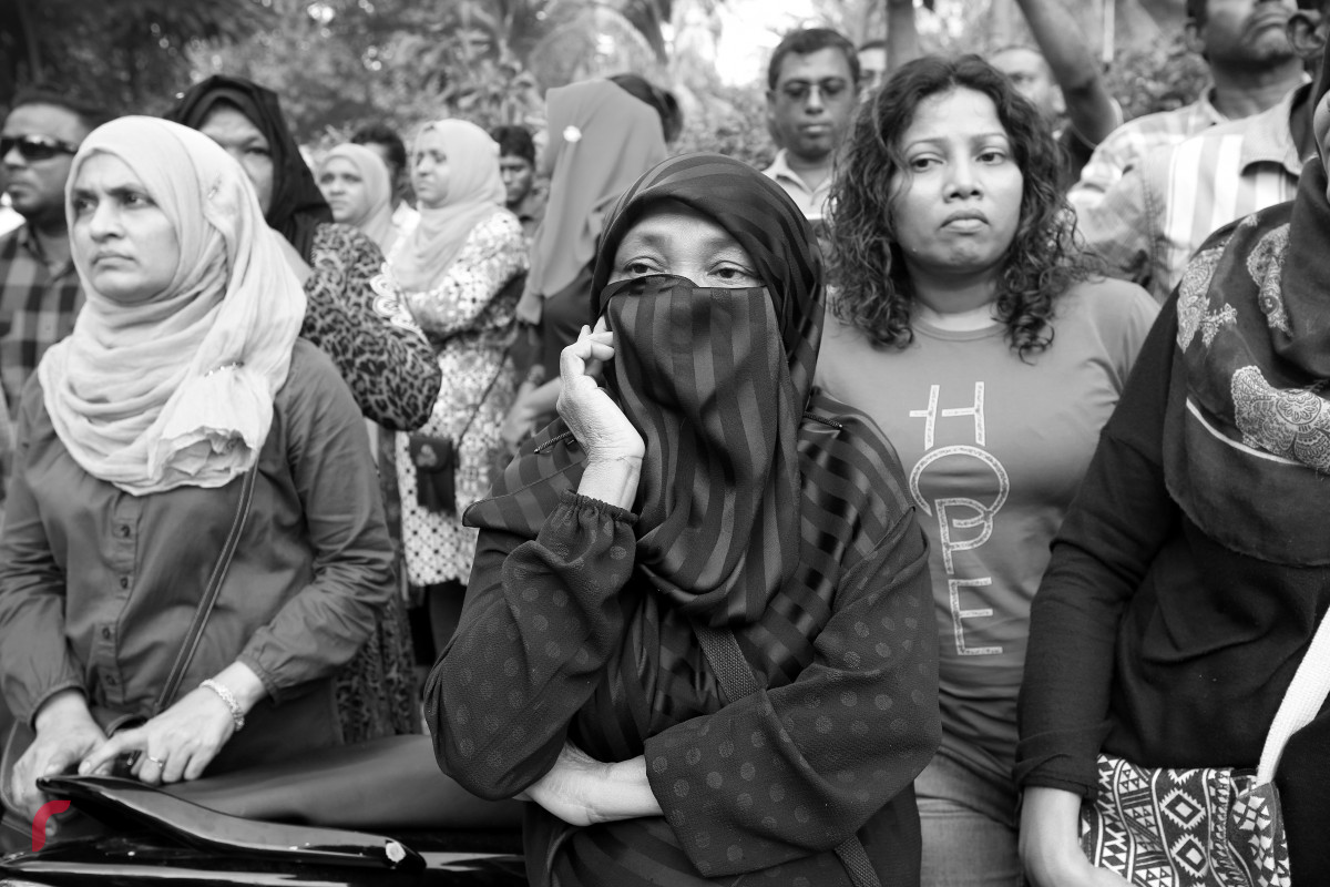 މުޒާހަރާގެ ބައިވެރިއަކު ޕެޕަރ ސްޕްރޭގެ އަސަރުން ސަލާމަތްވުމަށް މޫނު ނިވާކޮށްގެން