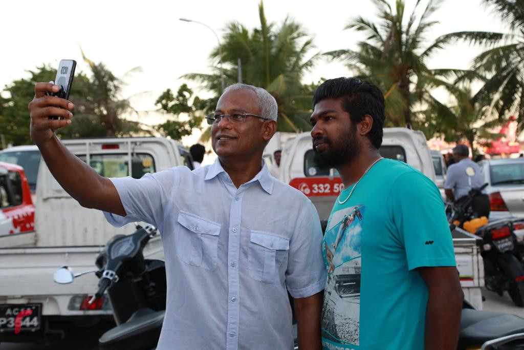 19 އޮކްޓޯބަރ 2018: ރިޔާސީ އިންތިޚާބުގައި ގުޅިފައިވާ ޕާޓީތަކަށް ލިބުނު ކާމިޔާބާއި ގުޅިގެން އުފާ ފާޅުކުުރުމަށް ހަރުގެ ސަރަހައްދުގައި ކުރިއަށްގެންދިޔަ ހަރަކާތުގައި އިންތިޚާބީ ރައީސް ރައްޔިތުންނާއި ބައްދަލުކުރައްވައި ފޮޓޯ ނަންގަވަނީ