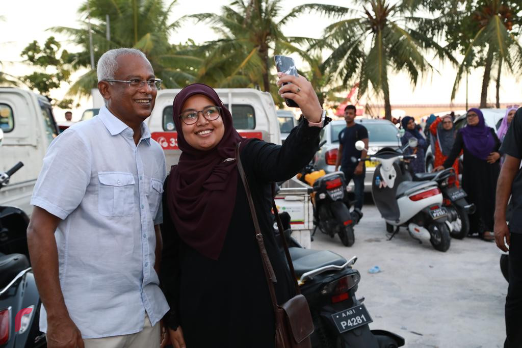 19 އޮކްޓޯބަރ 2018: ރިޔާސީ އިންތިޚާބުގައި ގުޅިފައިވާ ޕާޓީތަކަށް ލިބުނު ކާމިޔާބާއި ގުޅިގެން އުފާ ފާޅުކުުރުމަށް ހަރުގެ ސަރަހައްދުގައި ކުރިއަށްގެންދިޔަ ހަރަކާތުގައި އިންތިޚާބީ ރައީސް ރައްޔިތުންނާއި ބައްދަލުކުރައްވައި ފޮޓޯ ނަންގަވަނީ