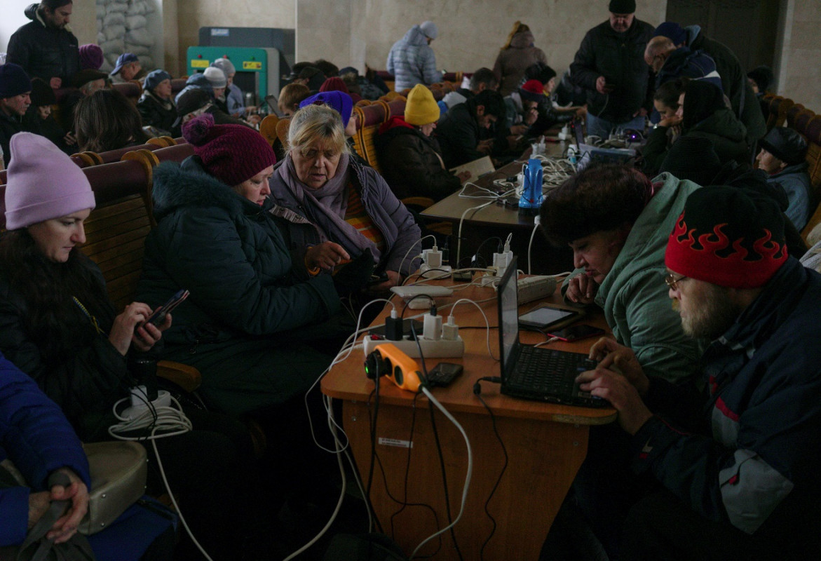 ރަޝިޔާގެ އަސްކަރިއްޔާ ޚަރސަން އިން ނިކުތުމަށްފަހު، އެއިސާބު ރައްޔިތުން އެމީހުންގެ އިލެކްޓްރޯނިކް ޑިވައިސްތައް ރޭލްވޭ ސްޓޭޝަނެއްގައި ޗާޖުކުރަނީ - ފޮޓޯ: ރޮއިޓަރސް