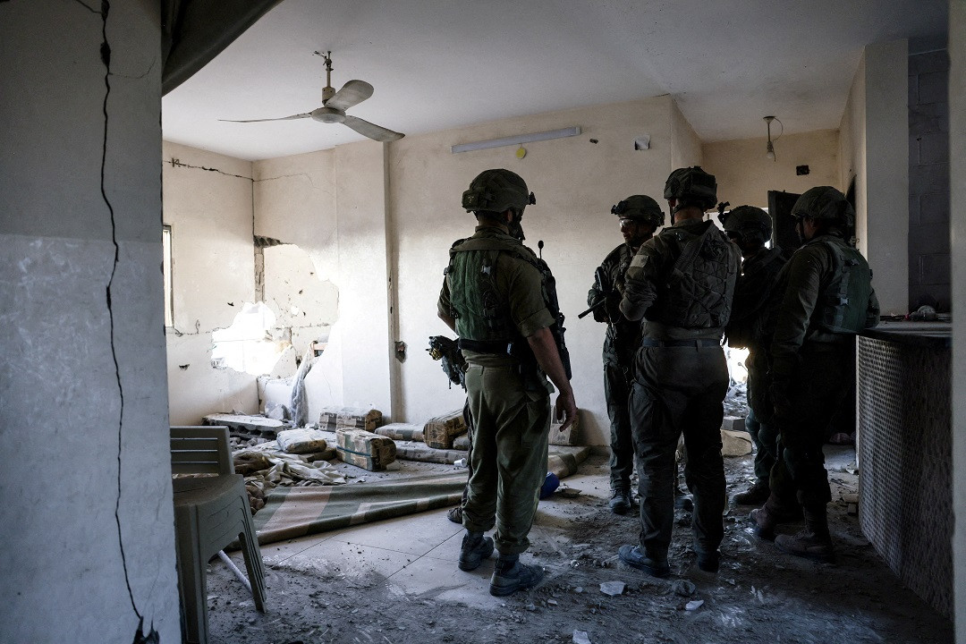 ޣައްޒާއަށް އަރައިގެން އުޅޭ އިސްރާއީލުގެ އަސްކަރީ އޮފިސަރުންތަކެއް، އެމީހުންގެ ބޮމުގެ ހަމަލާތަކުގައި ގެއްލުންލިބިފައިވާ ގެއެއްގެ ތެރޭގައި - ފޮޓޯ: ރޮއިޓަރސް