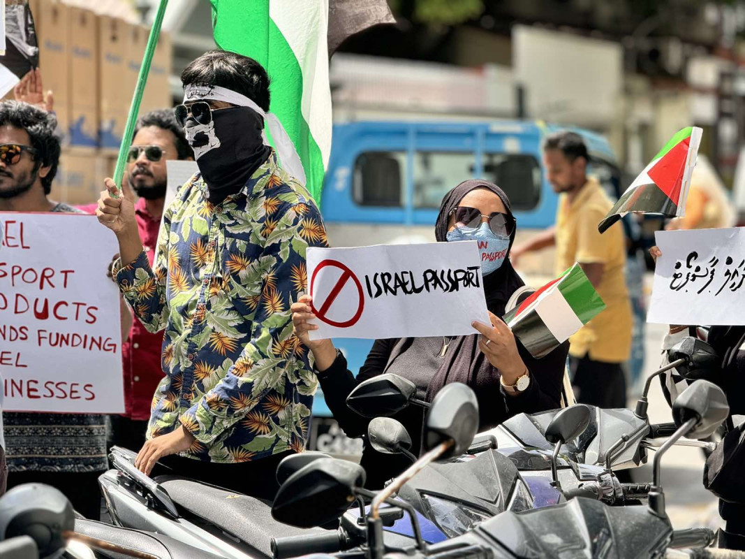 އިޒްރޭލް ޕާސްޕޯޓް މަނާކުރުމަށް ގޮވާލާ ކުރި މުޒާހަރާގެ ތެރެއިން - އެއްވުމަށް ދިޔަ ފަރާތްތަކުން ވަނީ އިޒްރޭލަށް އެެހީތެރިވެދޭ ފަރާތްތަކާއި، އުފެއްދުންތައްވެސް ރާއްޖެއަށް އެތެރެވުން މަނާކުރުމަށް ގޮވާލާ ލިޔެފައިވާ ބޯޑްތައް ހިފައިގެން އަޑު އުފުލާފަ - ފޮޓޯ: ޙުސައިން މަޚްތޫމް