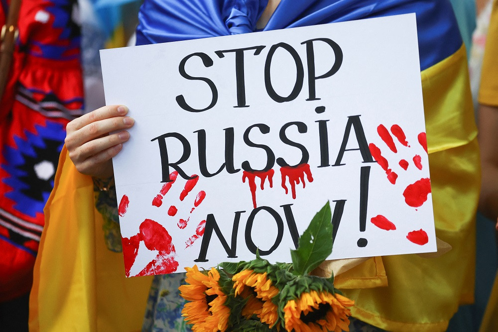 ޔޫކްރެއިންގެ މިނިވަން ދުވަހުގެ އެއްވުމުގެ ތެރެއިން, ލަންޑަންގެ ޑައުނިންގ ސްޓްރީޓްގައި މުޒާހަރާކުރަމުންދާ މީހަކު ބޯޑެއް ހިފައިގެން - ފޮޓޯ: ރީޖަނަލް އެއަރޕޯޓްސް