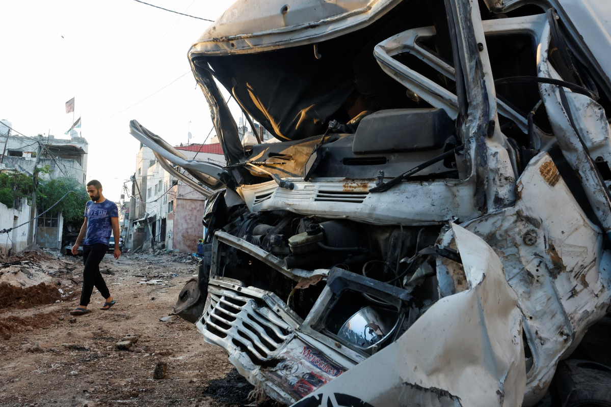 ޖެނިން ކޭމްޕުން އިސްރާއީލުގެ އަސްކަރިއްޔާ ފޭބުމަށްފަހު، ހަލާކުވެފައިވާ ވެހިކަލެއް ކައިރީގައި ފަލަސްތީނު މީހަކު ހިނގާފައި ދަނީ - ފޮޓޯ: ރޮއިޓަރސް