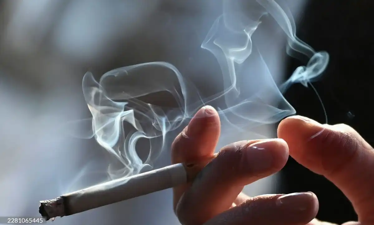 A person holding a lit cigarette.