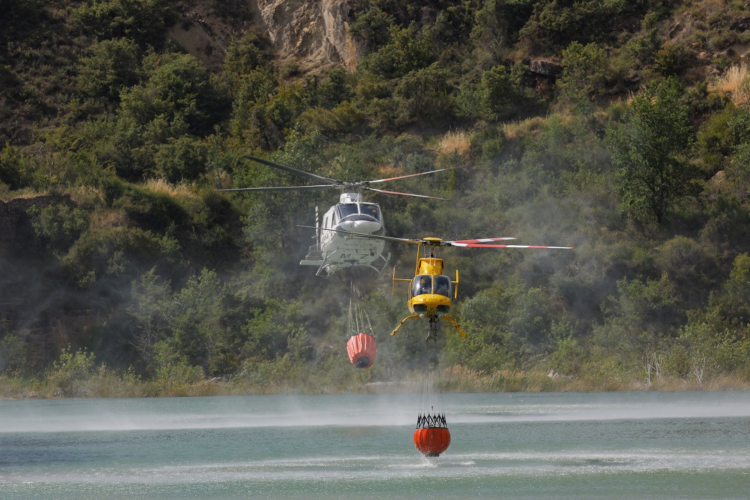 ސްޕެއިންގެ ކެޓުލޯނިއާގެ ޖަންގައްޔެއްގައި ރޯވި އަލިފާންގަޑު ކޮންޓްރޯލް ކުރުމަށް ހެލިކޮޕްޓަރުތަކުން ކޯރުން ފެންނަގައިގެން ގެންދަނީ - ފޮޓޯ: ރޮއިޓަރސް