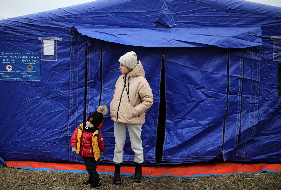 ޔޫކްރެއިން-ރަޝިއާ ހަނގުރާމަ: ޔޫކްރެއިނުން ރުމޭނިއާއަށް ދަތުރުކުރި އަންހެނަކާއި ކުޑަކުއްޖެއް ރެފުޖީންނަށް ހާއްސަކޮށްފައިވާ ޓެންޓެއް ކުރިމަތީގައި - ފޮޓޯ: ރޮއިޓަރސް
