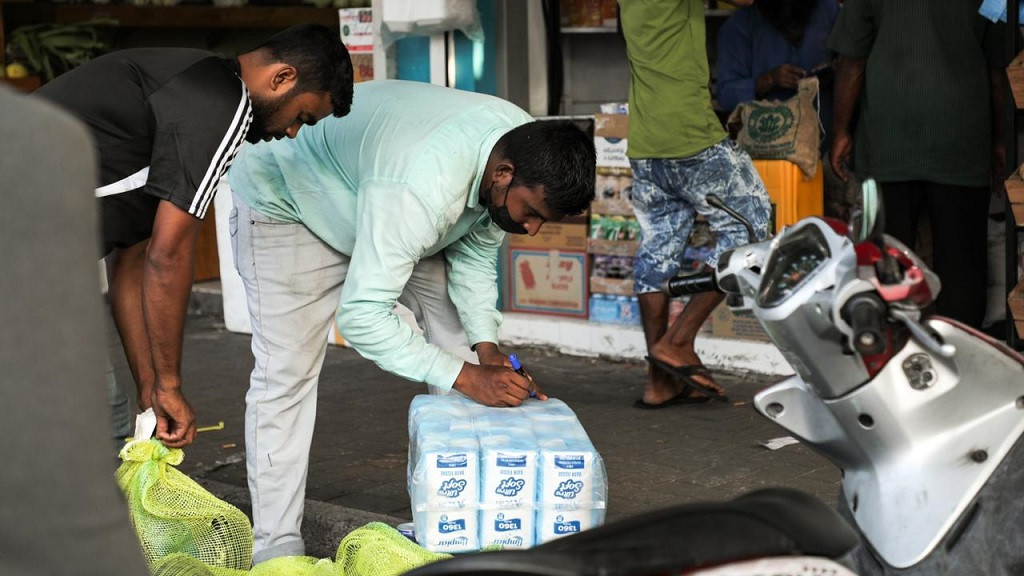 ބާޒާރުމަތީ ފިހާރައެއްގެ ކުރިމަތީގައި ދެ މީހާކު މުދާތަކެއް ގެންދިއުމުގެ މަސައްކަތުގައި - ފޮޓޯ: މުހައްމަދު އަނިލް