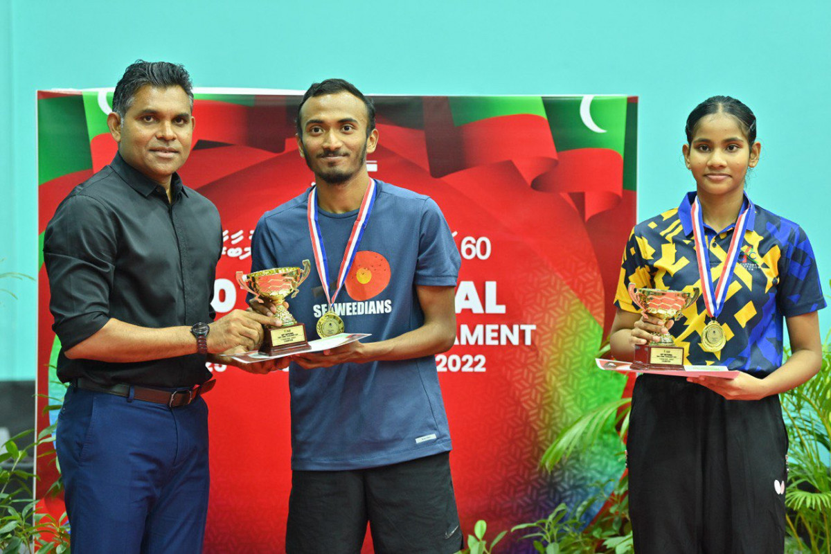 ޗެމްޕިއަން ޝައްފާނަށް ތަށި ހަވާލުކުރާއިރު އަންހެން ޗެމްޕިއަން ދީމާ ކައިރީގައި